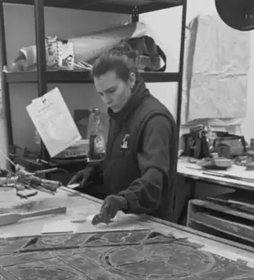 Flore Hunaut, cheffe d’atelier, travaillant sur un vitrail sur la table de l’atelier